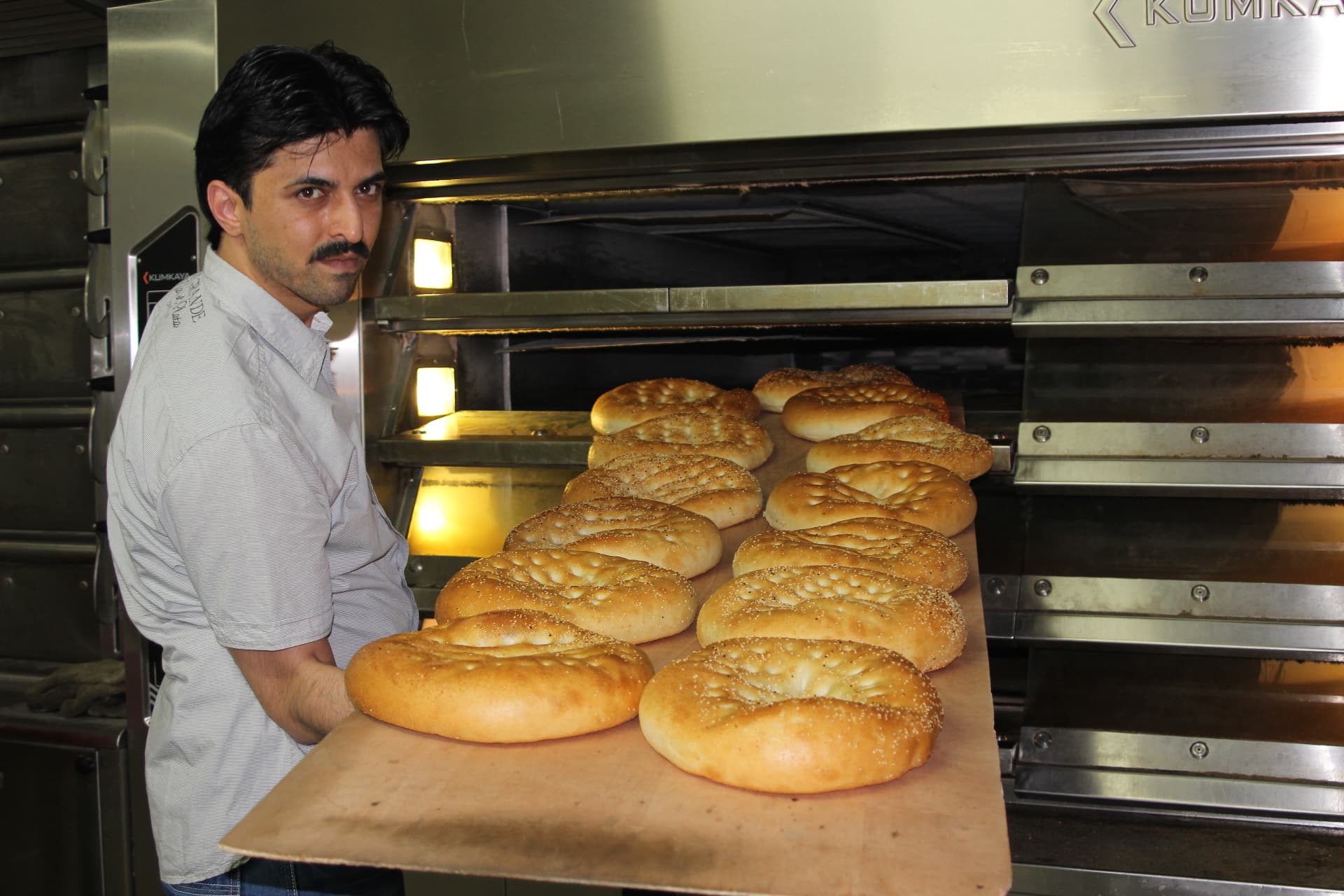 Bäcker der HAK Bäckerei zieht frische Fladenbrote aus dem Ofen