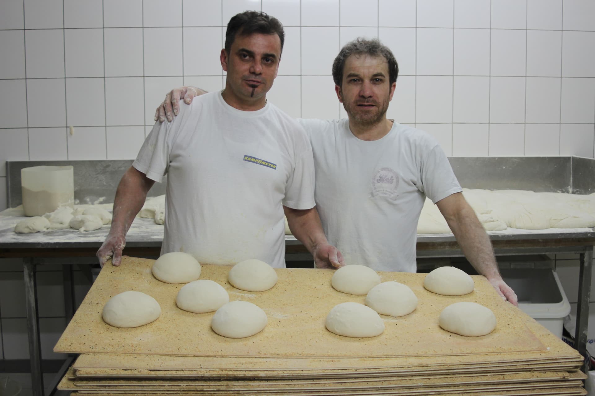 Zwei Bäcker der HAK Bäckerei mit frischen Teiglingen in der Backstube